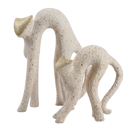 Abstract cat figurines in a textured cream stone-like finish with metallic gold accents on the ears, shown on a plain white background.