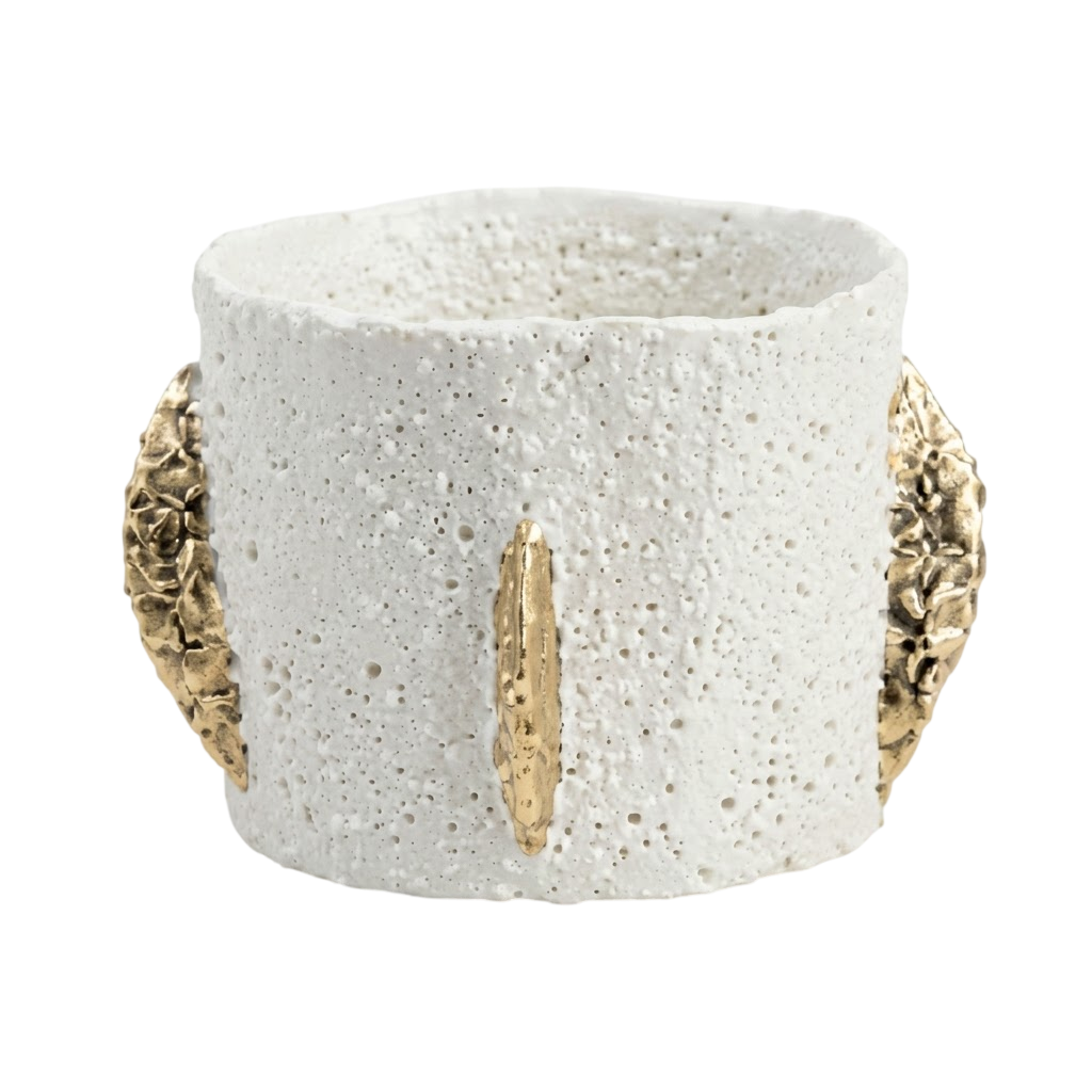 A textured white ceramic cuff bracelet with gold leaf accents on the front and sides, set against a plain white background.