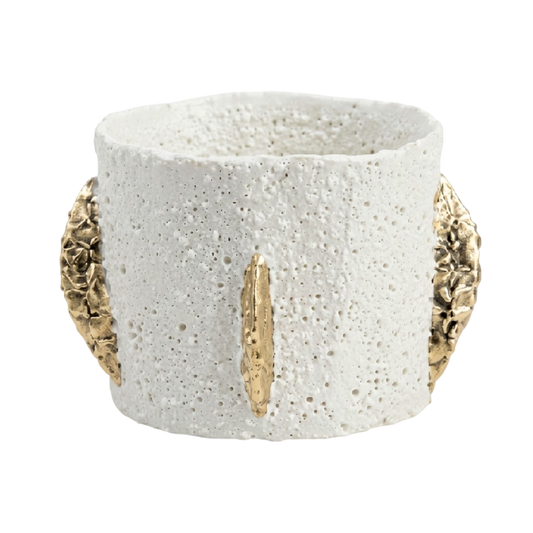 A textured white ceramic cuff bracelet with gold leaf accents on the front and sides, set against a plain white background.