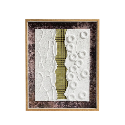 A framed abstract art piece featuring a vertical textured split design with a white crumpled-texture left side, a gold grid-patterned center strip, and a white right side with raised circular ring shapes, all set in a dark mottled background and a light wood frame.
