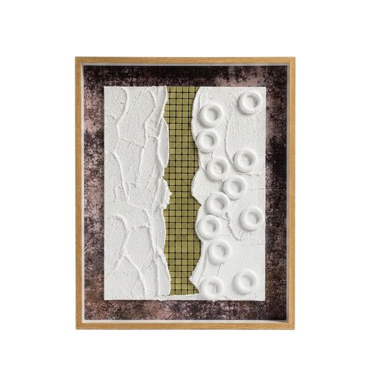 A framed abstract art piece featuring a vertical textured split design with a white crumpled-texture left side, a gold grid-patterned center strip, and a white right side with raised circular ring shapes, all set in a dark mottled background and a light wood frame.