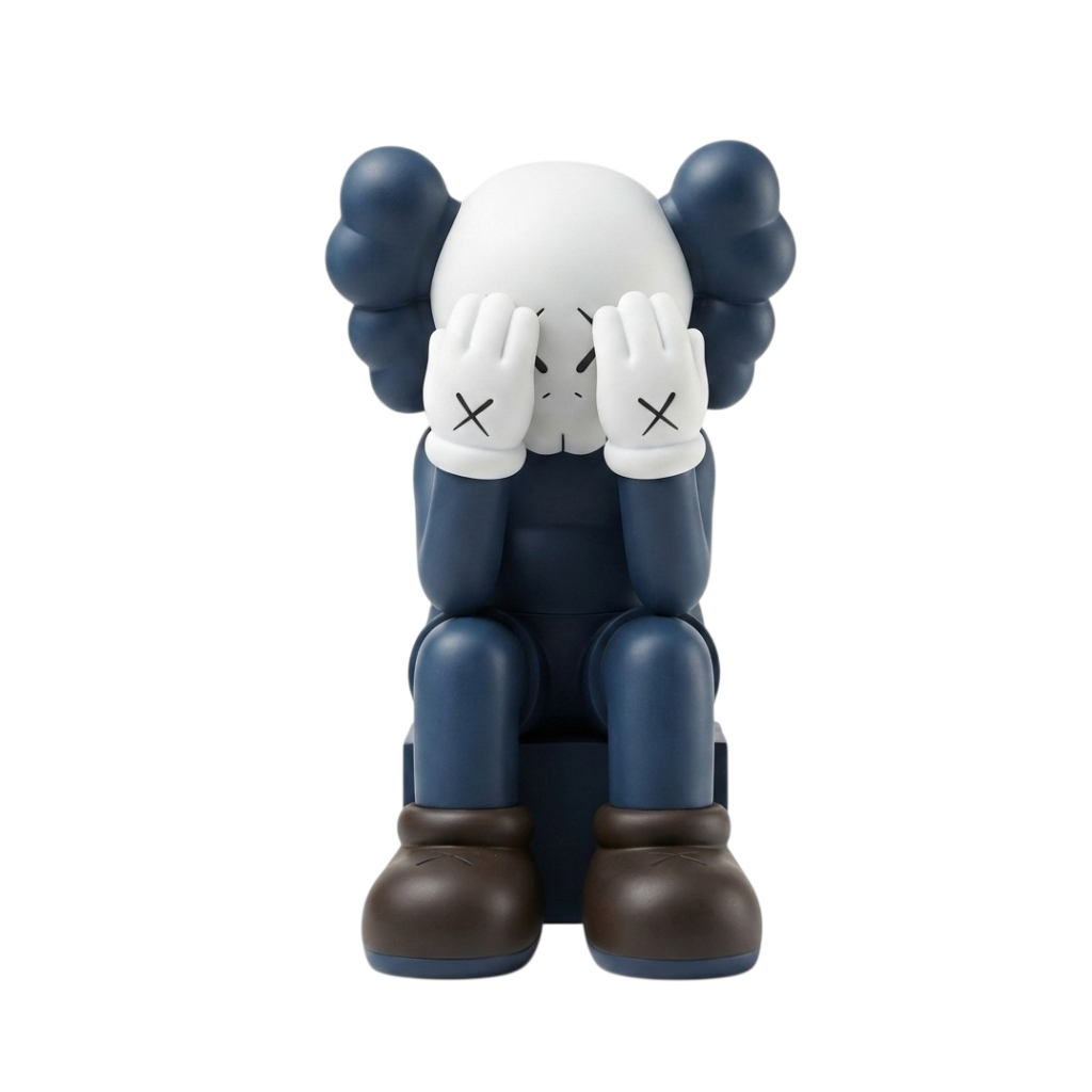 A stylized seated figurine resembling a character with a white head, dark blue body, dark blue hair-like shapes, white gloves with black X marks, and dark brown boots, centered on a plain white background.