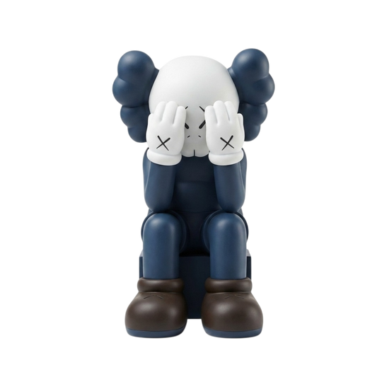 A stylized seated figurine resembling a character with a white head, dark blue body, dark blue hair-like shapes, white gloves with black X marks, and dark brown boots, centered on a plain white background.