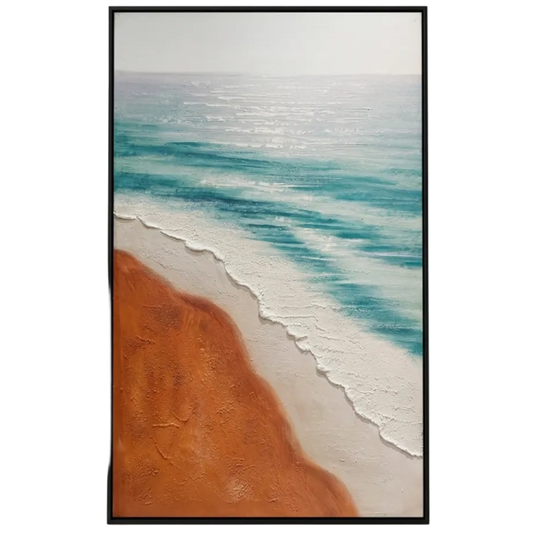 Framed artwork of a beach scene with blue water and orange sand on a white wall.