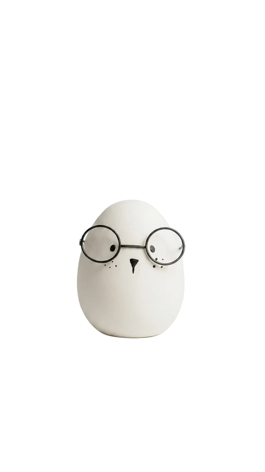 White ceramic owl with black glasses on a white background