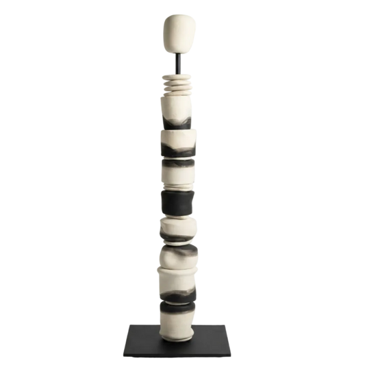 Black and white ceramic sculpture on a stand against a white background